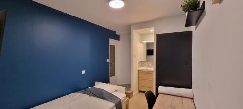 - une chambre avec un mur bleu et un lit dans l'établissement Chambres avec douche privative dans appartement partagé - Metro - Wifi, à Toulouse