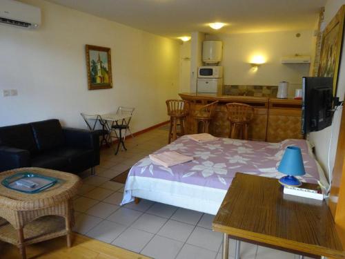 a room with a bed and a table and a kitchen at Fare Arearea Sweet Studio in Papeete