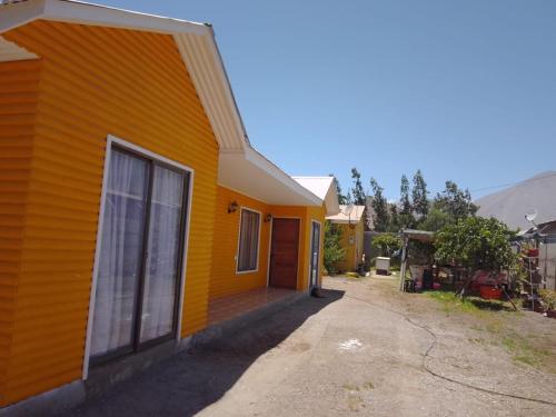 a yellow house with a porch on the side of it at Granja Vip Valle de Elqui in Vicuña