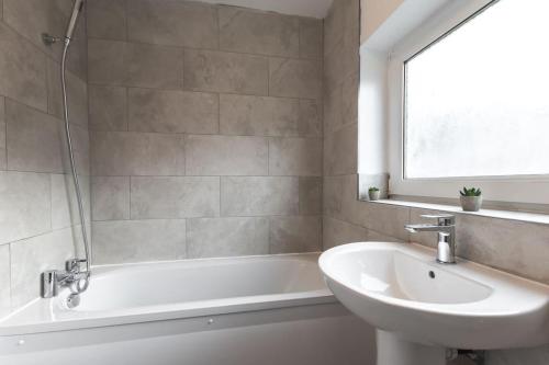ein Badezimmer mit einem Waschbecken, einer Badewanne und einem Waschbecken in der Unterkunft Beautiful 4 bedroom house in Reading
