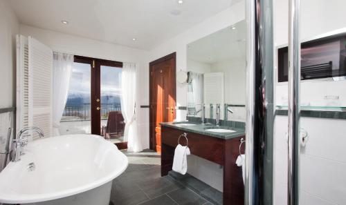 a white bathroom with a tub and a sink at Holbeck Ghyll Country House Hotel with Stunning Lake Views in Windermere