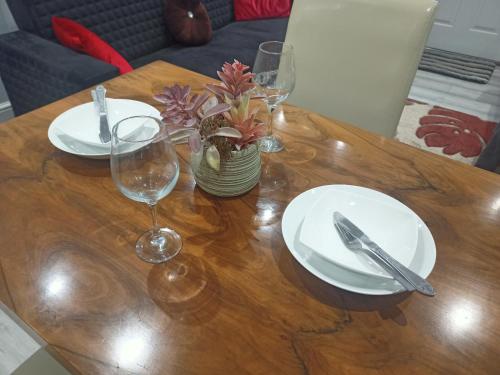 a wooden table with white plates and glasses on it at Newport rental property Furnished studio near train station Free Wifi Parking in Newport