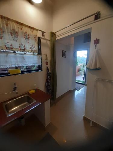 una cocina con fregadero y una puerta a una habitación en Cornwall for Couple, en Madikeri