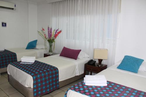 a hotel room with two beds and a vase of flowers at Hotel Kamani Florencia in Florencia