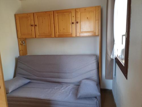 um pequeno quarto com uma cama e armários de madeira em Enjoy em Puy-Saint-Vincent