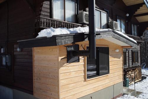 a log cabin with snow on the roof at björk （森の宿 ビヨルク） in Myoko