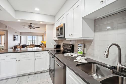 a kitchen with white cabinets and a sink at Villa Madeira 206 in St Pete Beach