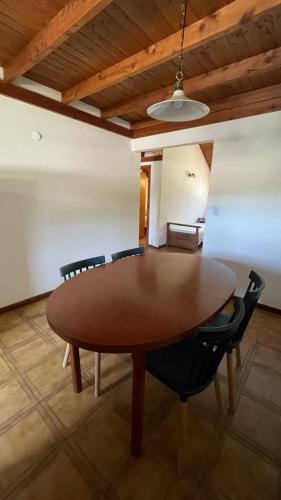 una mesa de madera en una habitación con sillas alrededor en Alice alojamiento en San Martín de los Andes