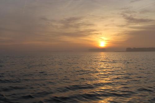 a sunset over the water with the sun in the sky at B&B Veluwemeerpension in Nunspeet