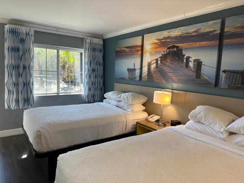a room with two beds and a painting of a pier at Days Inn by Wyndham Pensacola - Historic Downtown in Pensacola