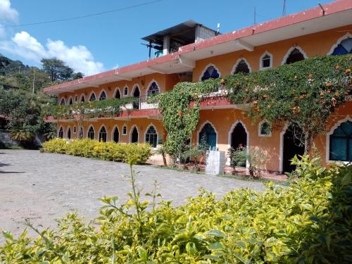 pomarańczowy budynek z dużo bluszczu na nim w obiekcie Hotel y Restaurante Tzutujil w mieście San Lucas Tolimán