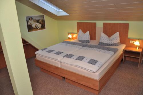 a bedroom with a large bed with white sheets and pillows at Cafe Hoyer Pension und Appartements in Rödigsdorf