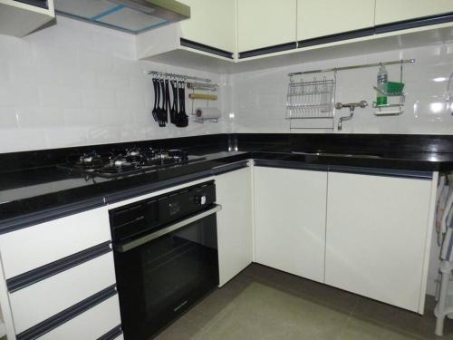 cocina con armarios blancos y fogones negros en Apartment in Rio with parking, en Río de Janeiro