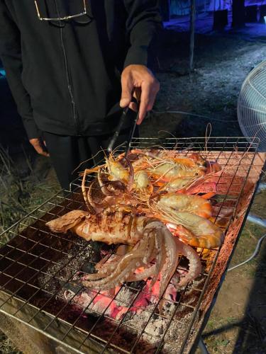 a person is grilling a lobster on a grill at อุ่นฟ้าอิงดาว A-frame 2 in Ban Kom