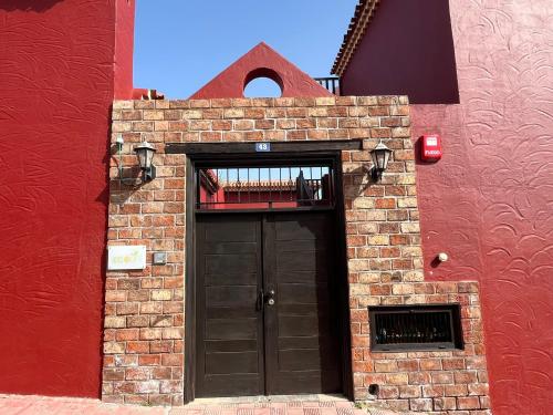 Hotel Ecolife Tenerife في سان ميغيل ذي أبونا: مبنى من الطوب وباب اسود وجدار احمر
