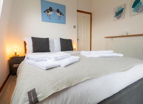 a bedroom with a large white bed with towels on it at Beach View Apartment in Stonehaven