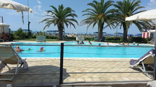 een zwembad met palmbomen en mensen erin bij Sea Horse in Lido di Camaiore