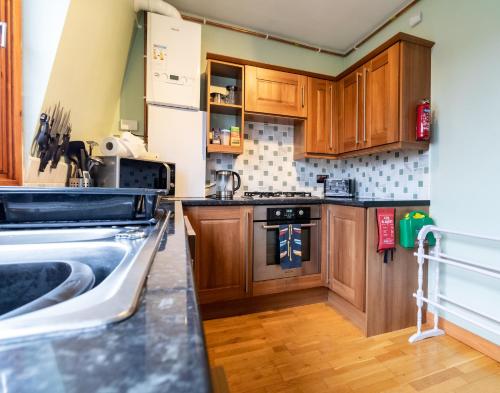 a kitchen with wooden cabinets and a sink at Beach View Apartment in Stonehaven