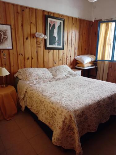 ein Schlafzimmer mit einem Bett in einem Zimmer mit Holzwänden in der Unterkunft La Guarida in La Bolsa