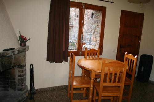 una mesa de madera y sillas en una habitación con ventana en Cal Xesc, en Castellar de NʼHug