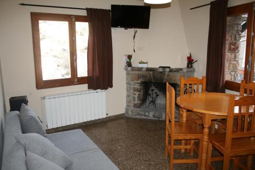 sala de estar con mesa y chimenea en Cal Xesc, en Castellar de NʼHug