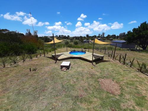una pequeña piscina en un campo con sombrillas en ALMA VERDE BUNGALOWS en La Paloma