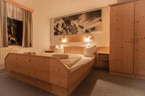 a bedroom with a wooden bed and a desk at Bauernhof Stempf - Appartement "HOCHARN" in Heiligenblut