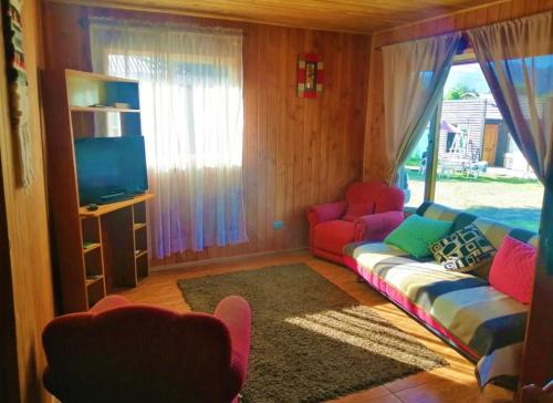 een woonkamer met een bank en een tv bij CABAÑAS MILKAHUE PUCON in Pucón