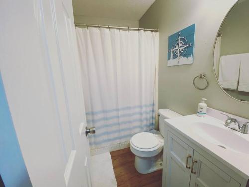 a bathroom with a toilet and a sink and a mirror at White Sand Getaway steps from Beach in Gulfport