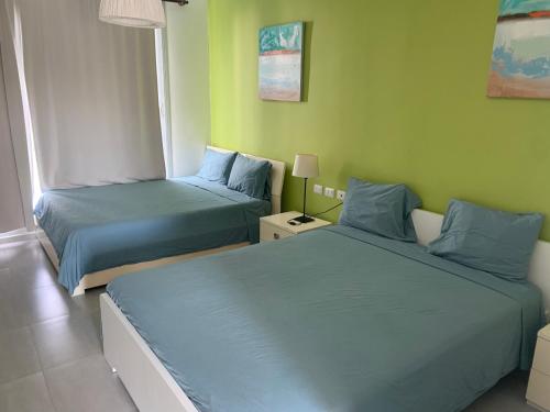 two beds in a room with green walls at Villa Real Playa Nueva Romana in La Romana