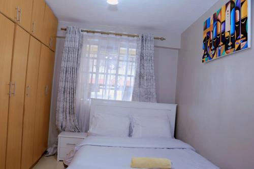 een slaapkamer met een wit bed en een raam bij Lovely 3 bedroom apartment, kisii in Kisii