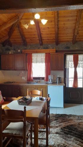 una cocina con mesa y sillas y una cocina con techos de madera. en Guesthouse Sofia en Palaios Agios Athanasios
