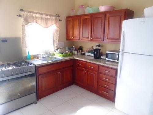 cocina con armarios de madera y nevera blanca en Simpson's residence, en Lucea