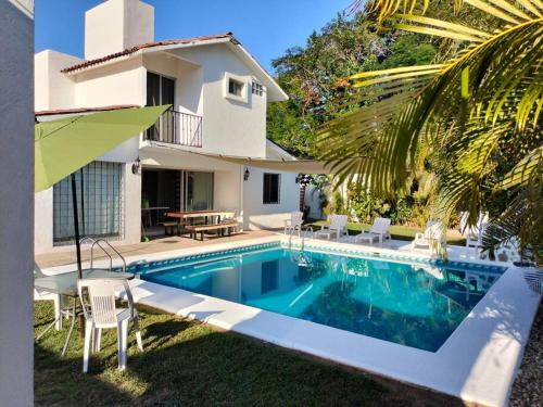 a villa with a swimming pool in front of a house at Casa Zihuana in Ixtapa
