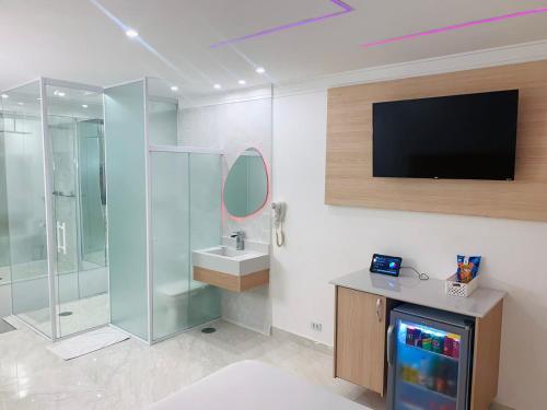 uma casa de banho com chuveiro e uma televisão na parede em Studio Motel (Adult Only) em Santos