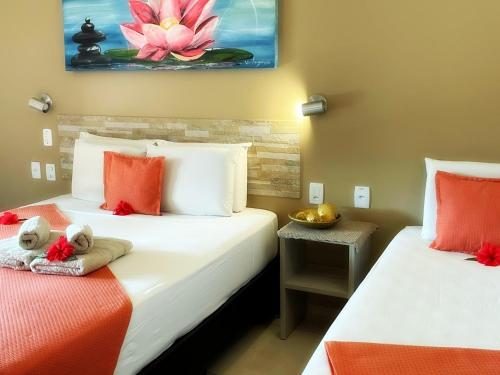 two beds in a room with orange and white at Pousada CasAlice in Jericoacoara