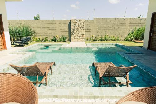 una piscina con due sedie e un tavolo di Casa Kairós no Shamballa by Qavi a São Miguel do Gostoso