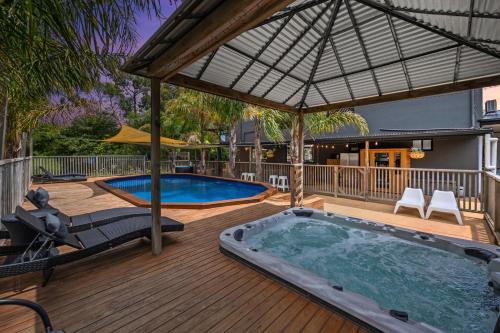 een hot tub op een houten terras met een parasol bij Elk Estate in Inverloch