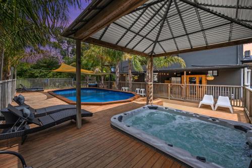 a hot tub on a wooden deck with an umbrella at Elk Estate in Inverloch