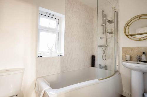 a white bathroom with a tub and a sink at Stillness- Connect to the Nature in the Hot Tub in Blandford Forum