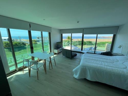 SYRAH Premium B2 - Balcón con vista al mar by depptö في بونتا دل إستي: غرفة نوم بسرير وطاولة ونوافذ زجاجية