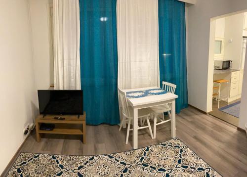 uma sala de estar com uma mesa e cortinas azuis em Luhtikadun Studio Apartment em Lahti