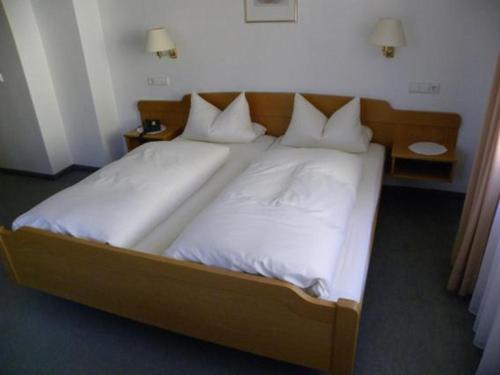 a large bed with white sheets and pillows at Hotel Restaurant Adler Bühlertal in Bühlertal