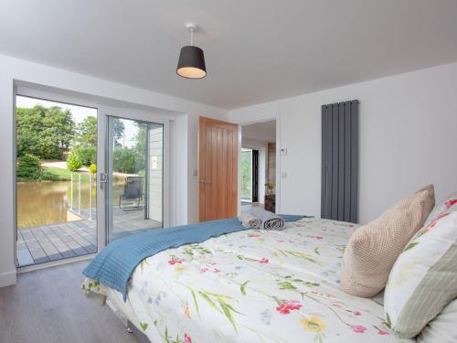 a bedroom with a bed and a sliding glass door at Kingfisher Lodge - Uk33889 in Cullompton