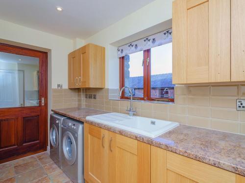 a kitchen with a sink and a washing machine at Rhiew Banc in Aberhafesp