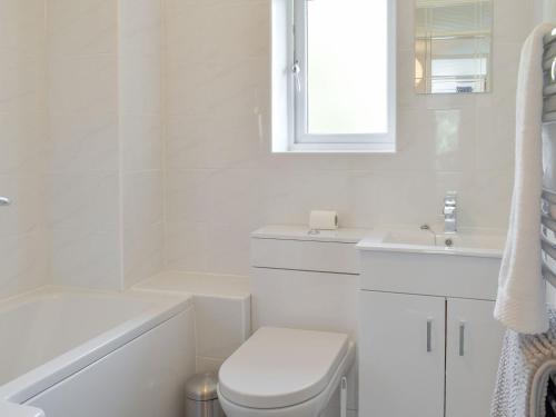 a white bathroom with a toilet and a sink at Stone Gardens in Broadstairs