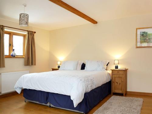 a bedroom with a large bed with white sheets at Cowslip Cottage in Brook