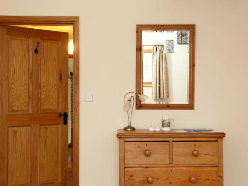 a mirror on top of a dresser next to a door at Cowslip Cottage in Brook