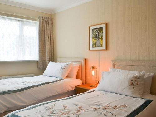 um quarto com 2 camas e uma mesa com um candeeiro em Jackdaw House em Bridlington