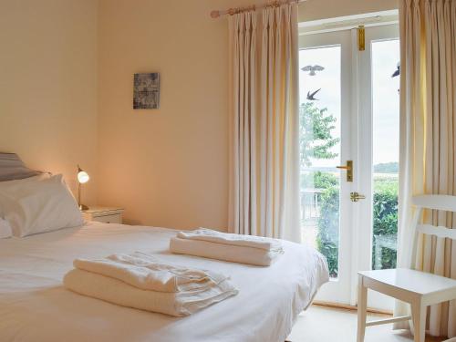 Len Cottage في Thurning: غرفة نوم بسرير أبيض مع نافذة كبيرة